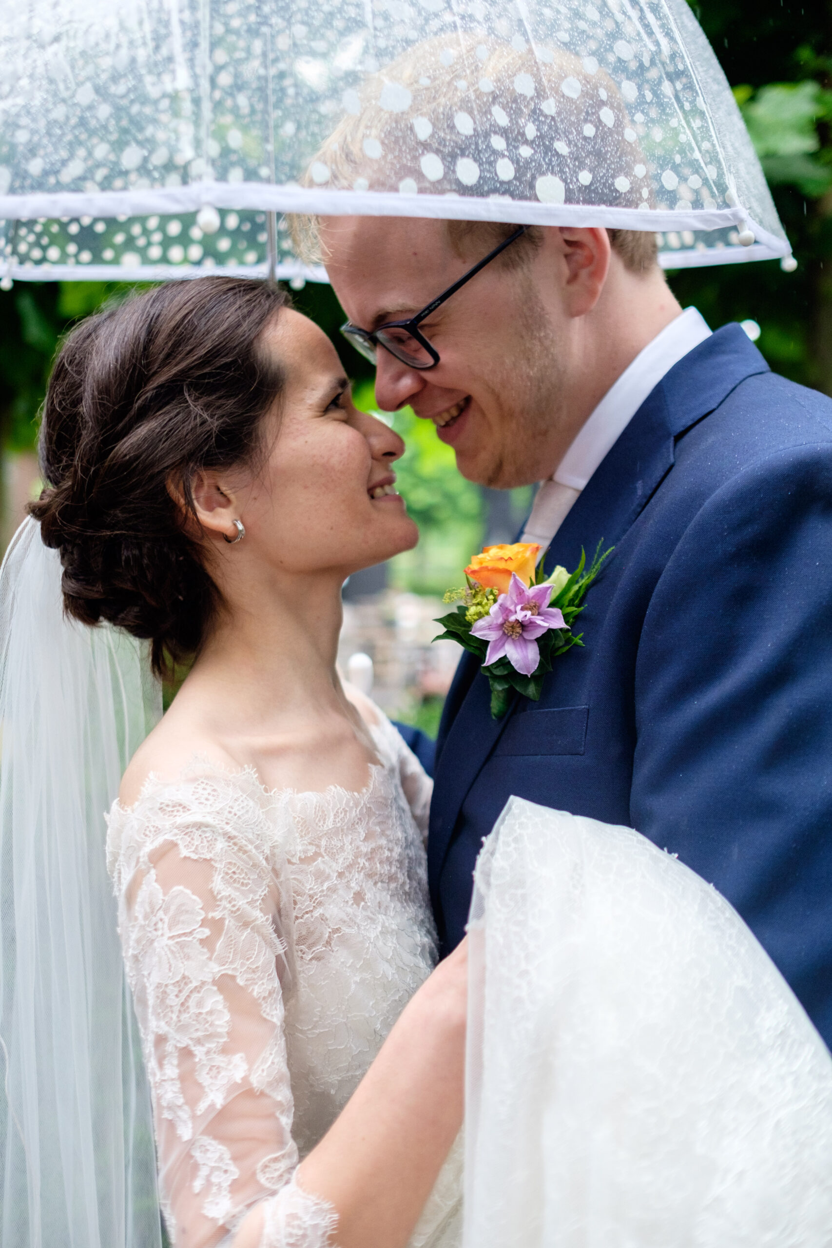 Bruidspaar onder transparante paraplu tijdens regen | Marieke van Dijk Fotografie
